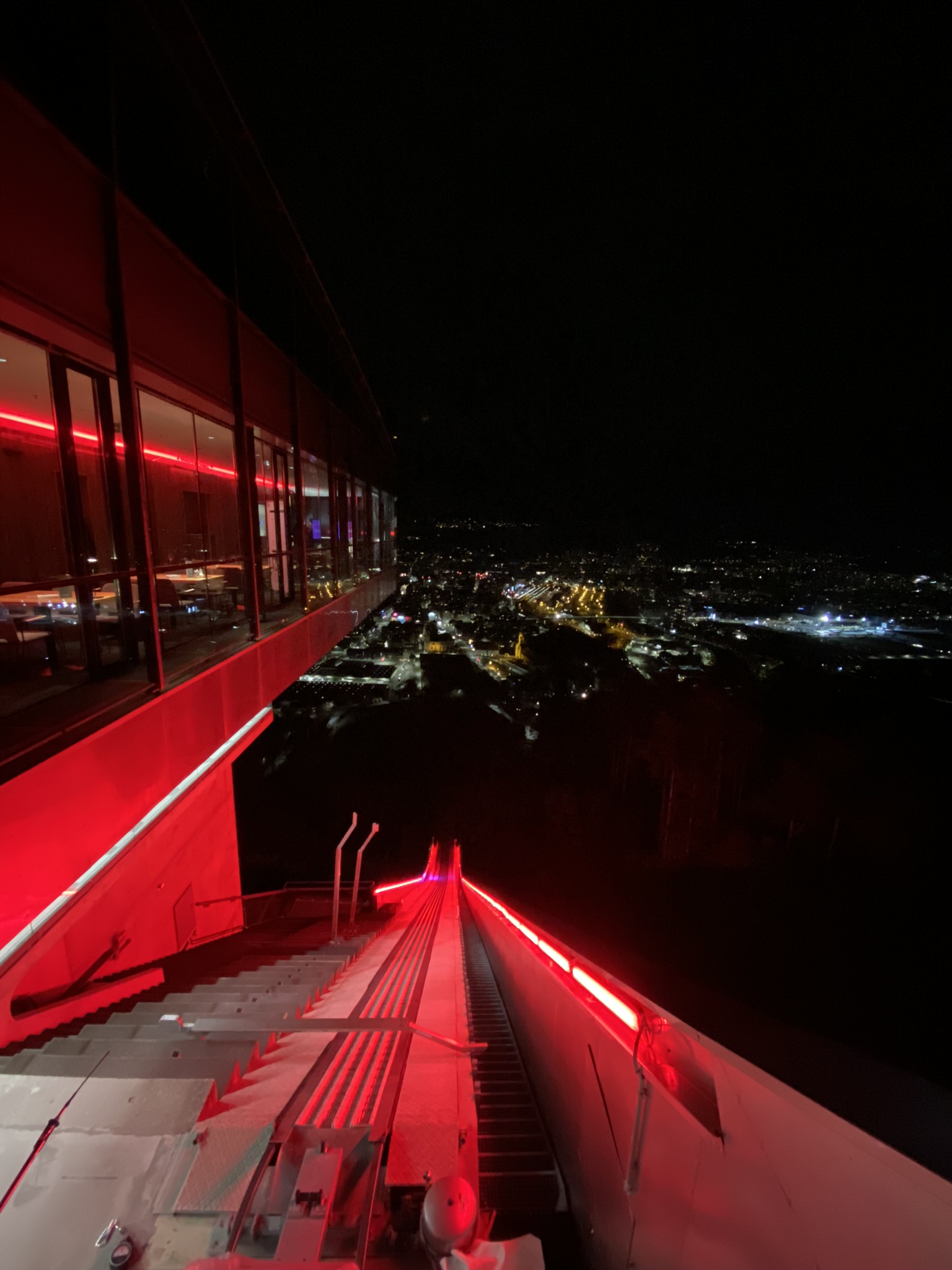 Red-lit stairs with Innsbruck city below at night, Hybriqe 2024