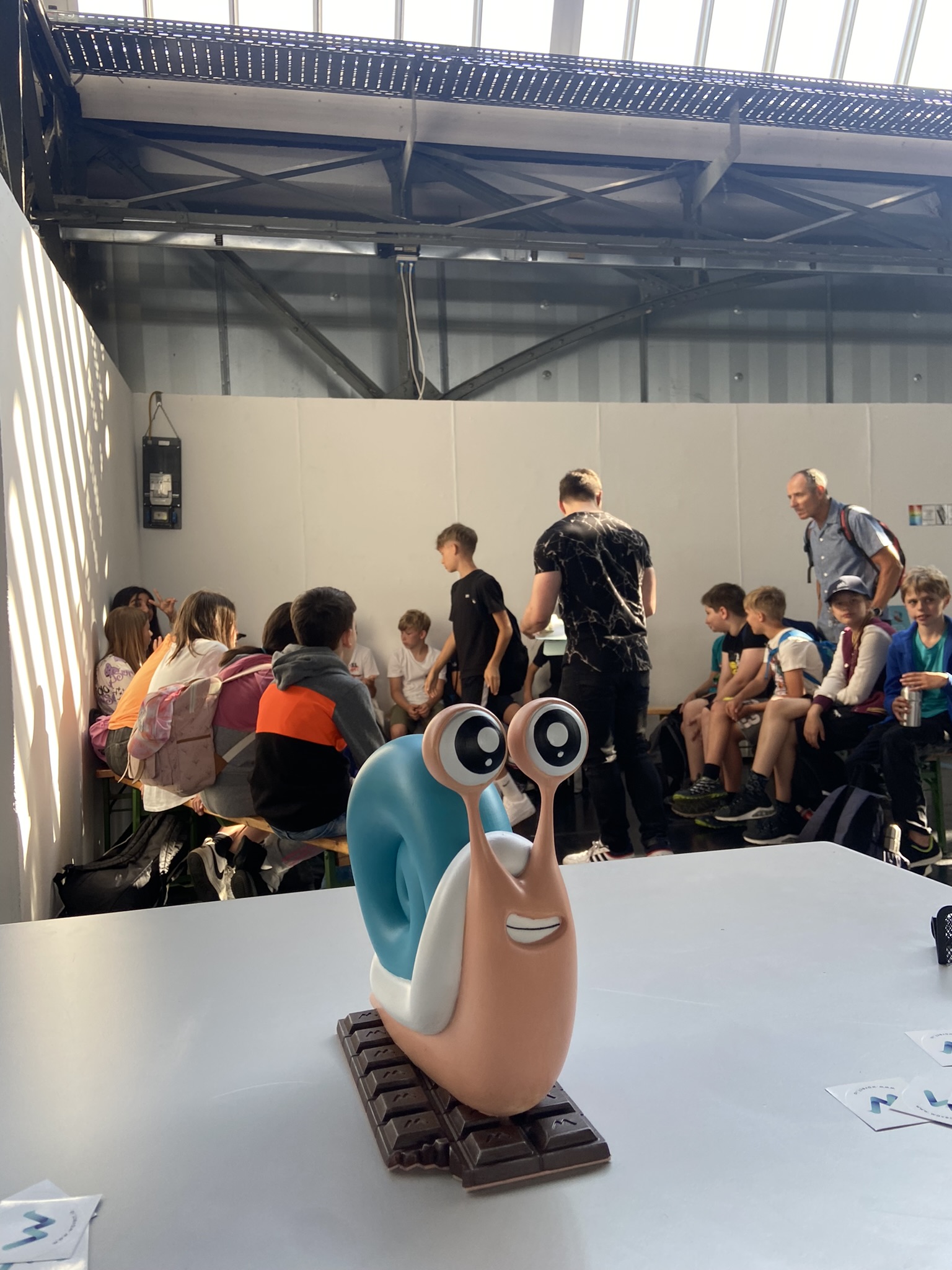 Wavect snail mascot in foreground, kids attending workshop at Kinder-Erlebnismesse 2024